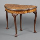 A 1930's oval Queen Anne style carved figured walnut card table raised on cabriole, ball and claw