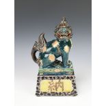 An Antique style Chinese glazed figure of a seated Dog of Fo raised on a plinth 28cm