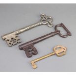 Two large church style door keys 25cm and a Continental gilt metal key decorated a coat of arms 17cm