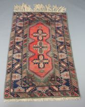 A pink, blue and green ground Afghan rug with 3 stylised medallions to the centre 191cm x 120cm In