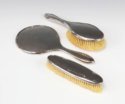 A silver 3 piece dressing table set comprising hand mirror, clothes brush and hairbrush Chester 1928