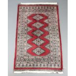 A red and white ground Bokhara rug with 5 diamonds to the centre 136cm x 80cmWear to the binding