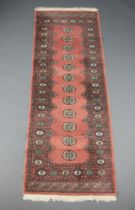 A pink and white ground Bokhara runner with 12 octagons to the centre within a multi row border