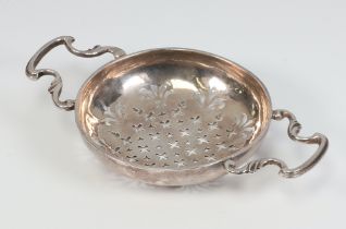 A Georgian silver pierced lemon strainer with scroll handles, 71 grams, 15cm, (hallmarks rubbed)