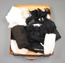 A fibre suitcase containing various fabrics including lace, fringing etc