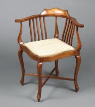 An Edwardian inlaid mahogany stick and rail back corner chair with upholstered seat, raised on