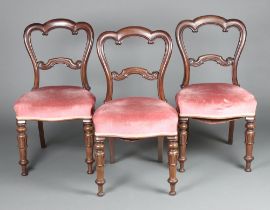 A set of 3 Victorian mahogany balloon back dining chairs with carved mid rails, raised on turned