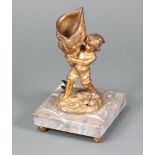 A 19th Century gilt metal match striker in the form of a standing boy with shell raised on a pink