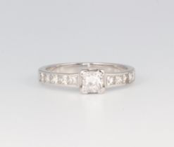 A white metal diamond ring with a princess cut centre stone approx. 0.25ct with diamond set