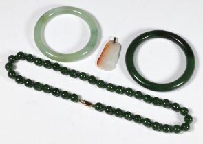 A dark green hardstone bangle 7cm diam., a pale green ditto 8cm, a dark green bead necklace 44cm and