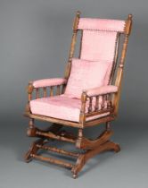 An American beech framed rocking chair with spindle turned decoration, upholstered in pink