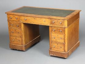 A Victorian light oak kneehole desk with green leather inset writing surface above 1 long and 8