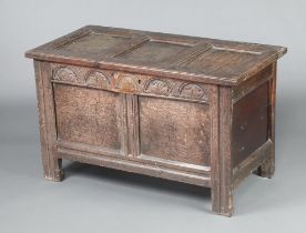 An 18th Century oak coffer of panelled construction with hinged lid and carved arcaded front panel