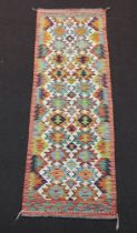 A white, turquoise and orange ground Chobi Kilim runner with 24 stylised medallions to the centre