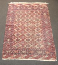 A red and white Bokhara rug with 24 medallions to the centre 208cm x 147cm In wear, slight stain