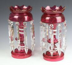 A pair of Victorian cranberry lustres with waisted stems and clear drops 35cm Extensive wear to