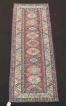 A white, orange and blue ground Caucasian runner with 10 octagons to the centre within a multi row