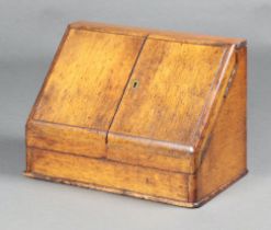 An Edwardian light oak wedge shaped stationery box with stepped fitted interior enclosed by panelled