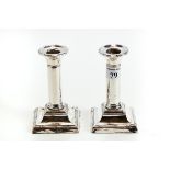 A PAIR OF GEORGE V SILVER CANDLESTICKS, plain columns on square reeded border bases, Chester 1910,