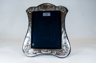 A large silver photo frame of shaped outline with floral decoration maker: D.R. & S., London 1983,