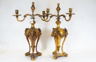 A pair of carved & gilded wood candelabra, triform ram's head & drapery design & hoofed monopodia,