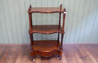 A Victorian mahogany serpentine fronted mahogany three-tier whatnot raised on spiral grooved