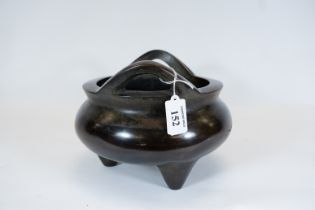 A Chinese twin handled bronze censer of compressed circular form on three feet, seal mark to base,