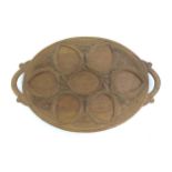 A carved wooden tray of oval form with scrolled handles, carved foliate decoration and seven