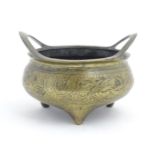 A Chinese cast twin handled three footed censer with incised dragon and phoenix decoration and