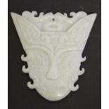 An Oriental carved hardstone pendant formed as a decorative mask. Approx. 3" Please Note - we do not