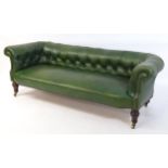 A late Victorian green leather deep buttoned Chesterfield sofa raised on turned tapering front
