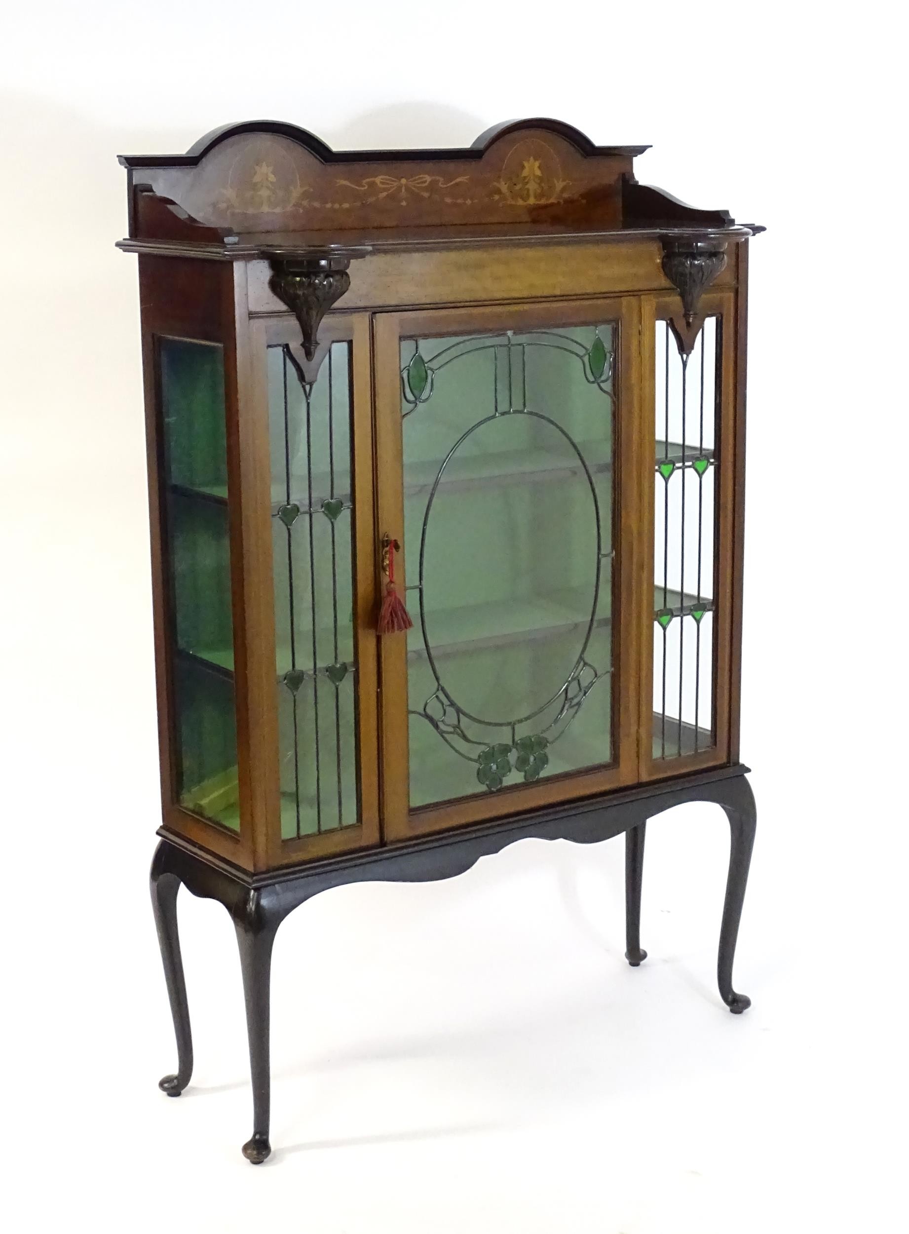An Edwardian mahogany display cabinet with leaded glass panelling, stained glass panels and a