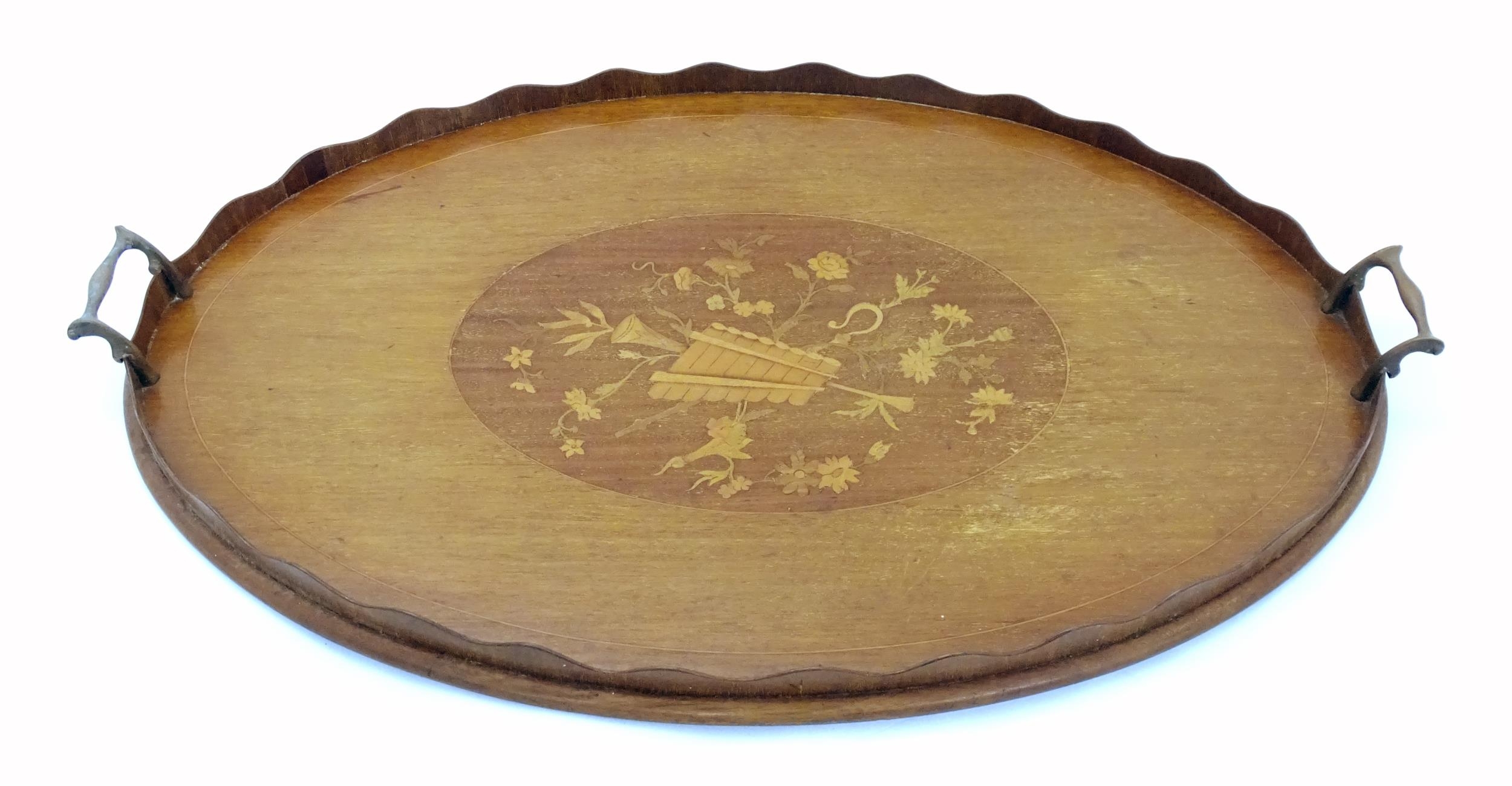 A late 19th / early 20thC mahogany tray of oval form with twin handles and central floral and