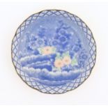 An Oriental blue and white plate with pink and green highlights depicting flowers. Character marks