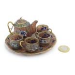 A plique a jour miniature tea set comprising teapot, four cups and a circular tray, each decorated