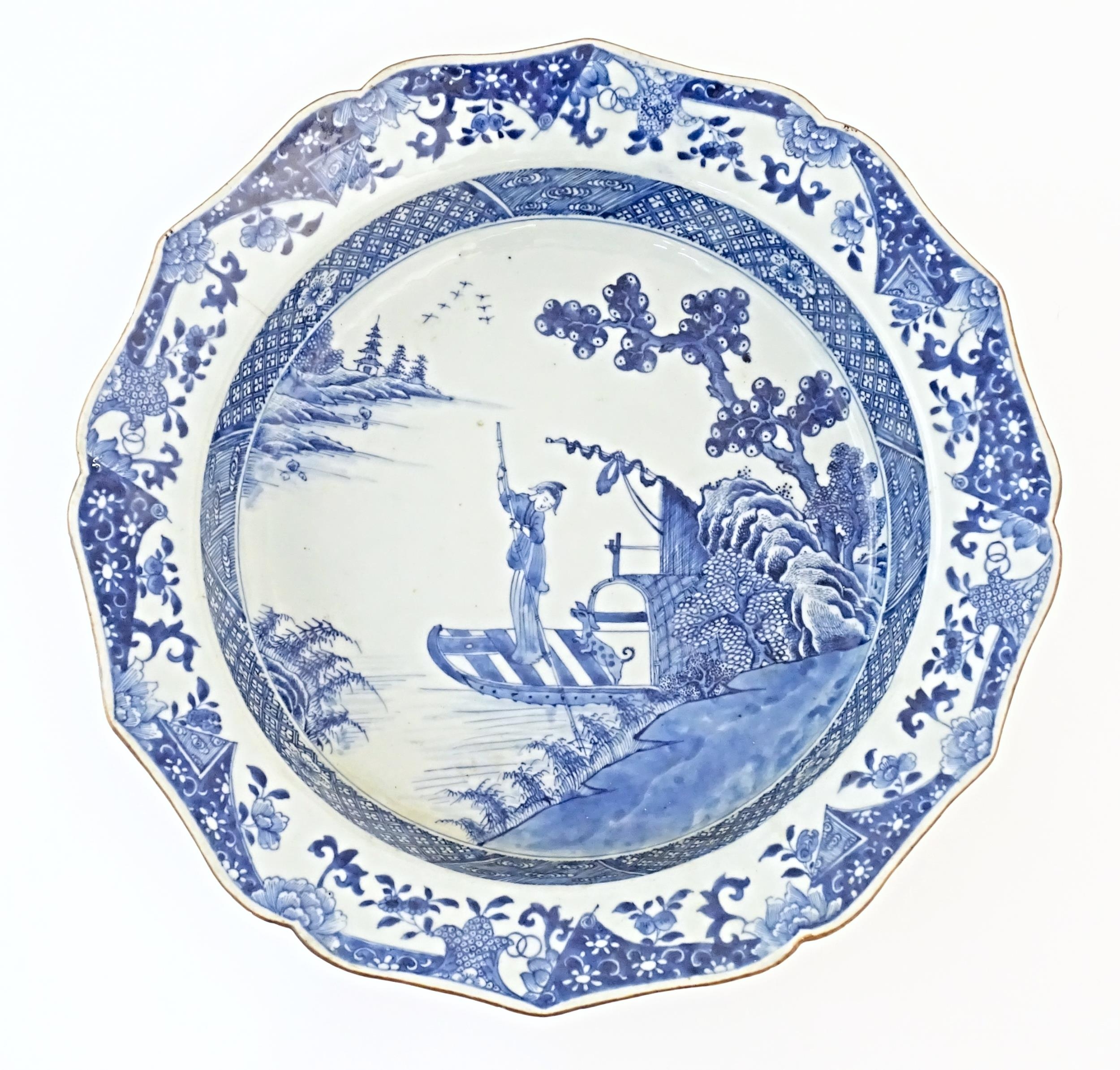 A Chinese blue and white bowl with shaped rim, decorated with a coastal scene with a figure and a