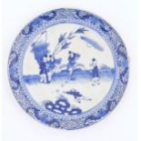 A Chinese blue and white plate decorated with figures in a garden landscape with apples. Approx. 8