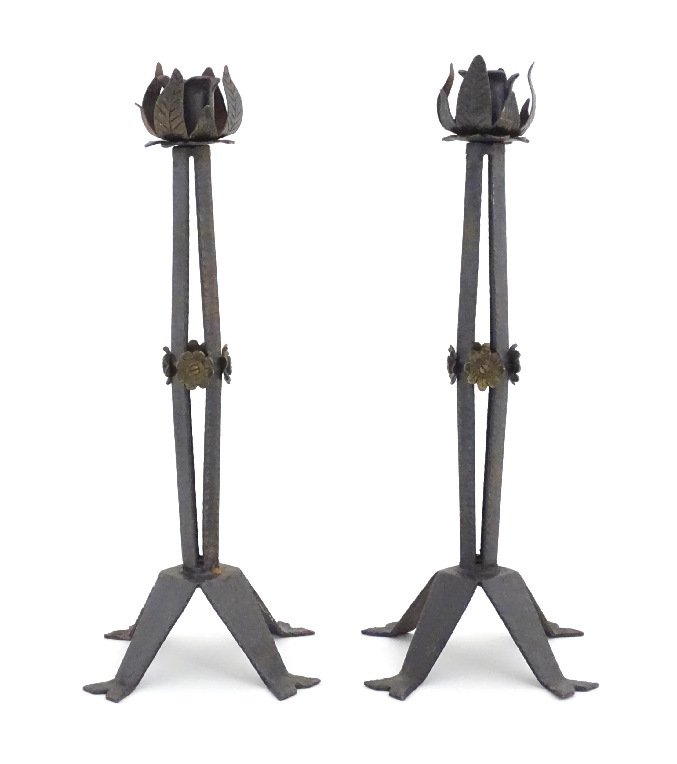 A pair of Arts & Crafts style wrought iron lamps with foliate detail to top and brass rosette detail