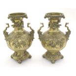 A pair of Oriental brass vases with twin handles formed as stylised beasts, the body decorated