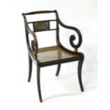 A Regency armchair with an ebonised finish, twist turned top rail, scrolled arms flanking a