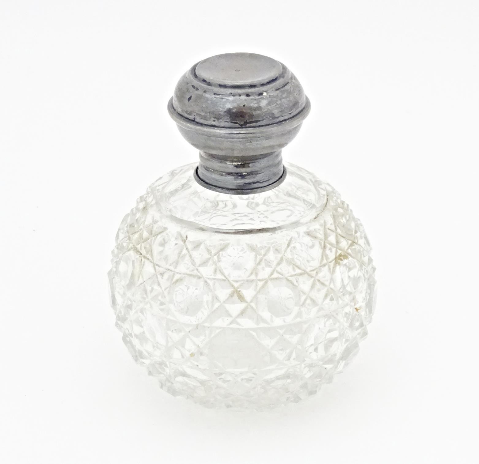 A cut glass scent / perfume bottle with silver top, hallmarked Birmingham 1919. Approx. 3 1/2"