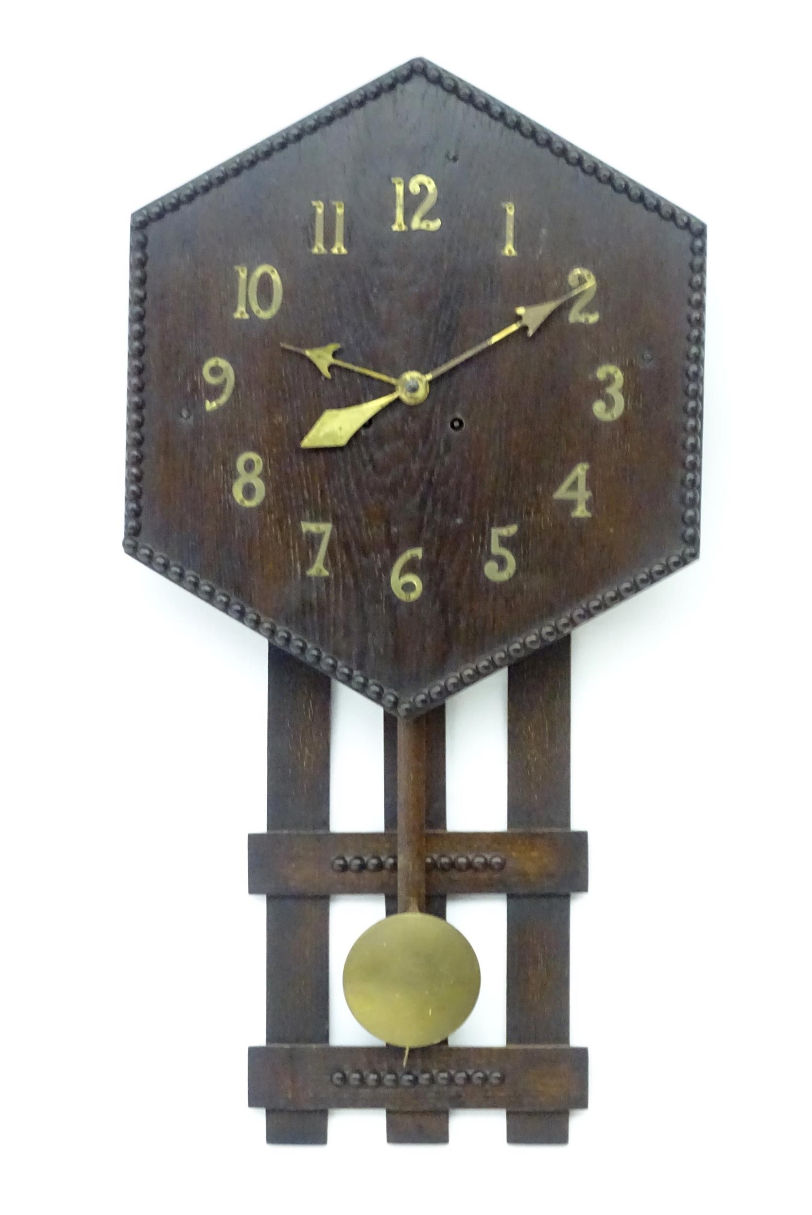 An Arts and Crafts style oak wall clock, the hexagonal dial with Arabic brass numerals and