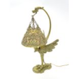 An early 20thC brass table lamp formed as a standing wyvern, the pierced brass shade suspended