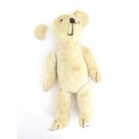 Toy: A 20thC plush teddy bear with stitched nose, mouth, eyes and paws. Approx. 19 1/2" long