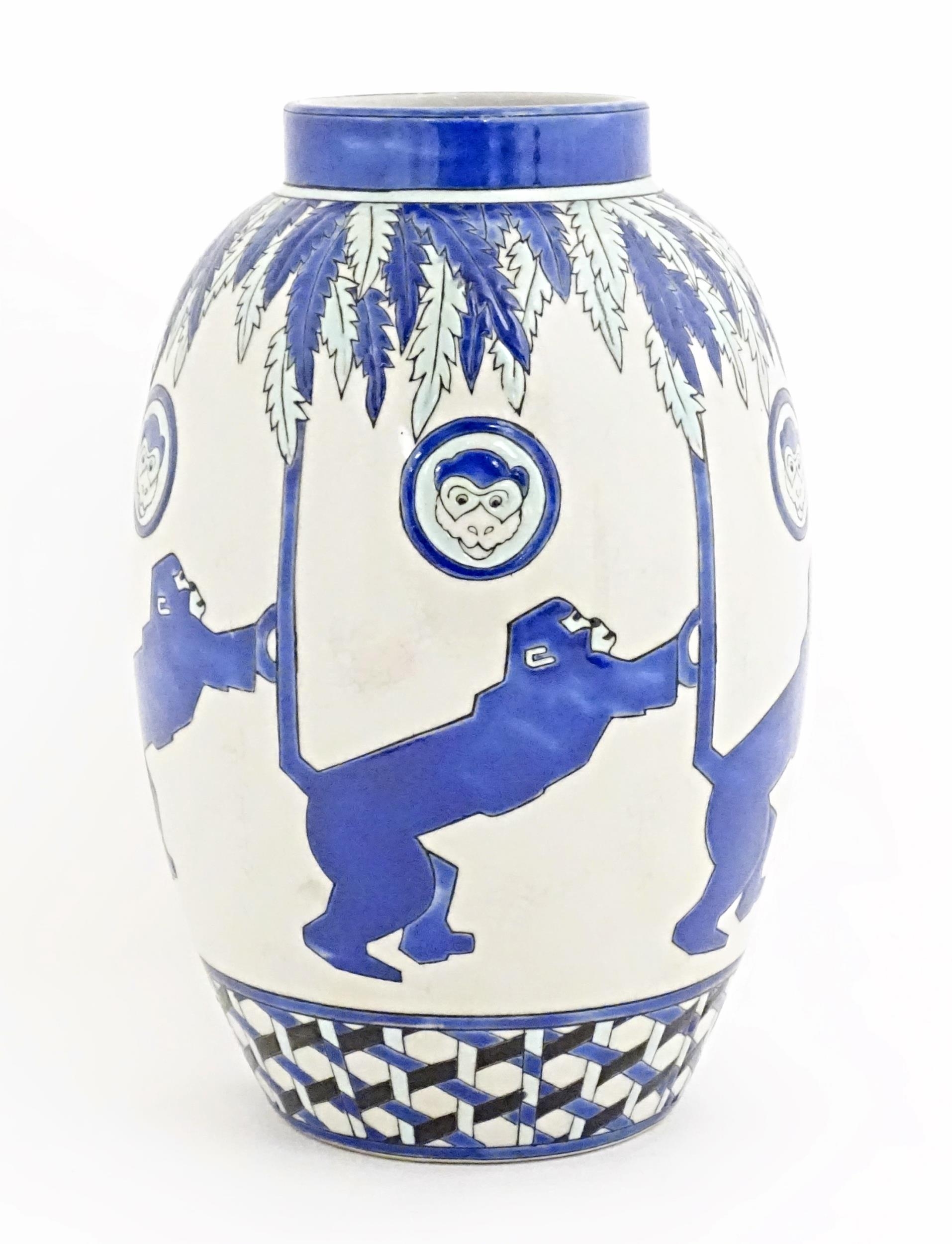 An Art Deco style blue and white vase decorated with banded monkey and palm tree detail. Marked