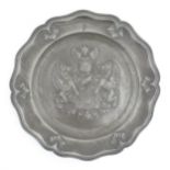 A pewter charger with shaped rim and central heraldic crest / coat of arms. Impressed crowned rose