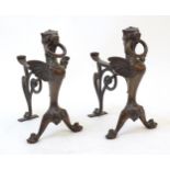 A pair of 20thC cast bronze fire dogs with winged griffin detail, paw feet, and scrolling support.