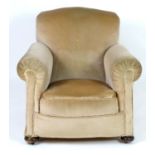 A mid 20thC Howard style armchair with scrolled arms and raised on squat bun front feet and