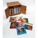 A retro teak record cabinet containing assorted vinyl records to include Louis Armstrong, Kenny