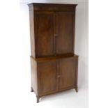 A late Georgian mahogany linen press with a moulded cornice above two sections with panelled doors